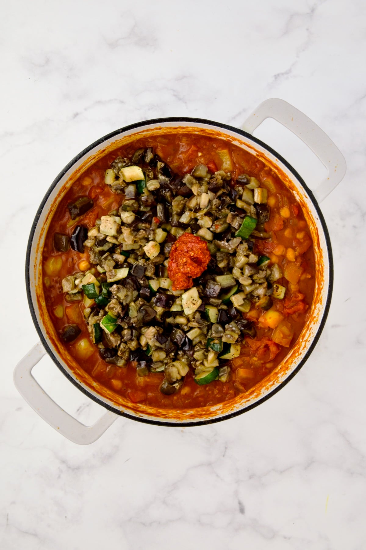Zucchini, eggplant and harissa added to stew.