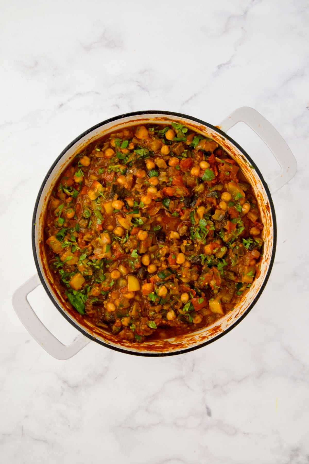 Finished Moroccan Eggplant Stew in white enamel cast iron skillet.