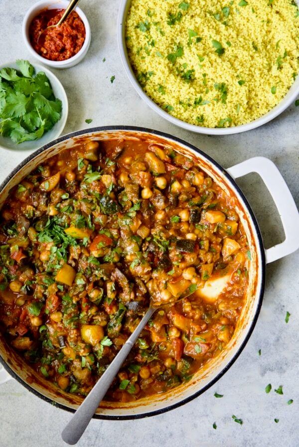 Finished Moroccan Eggplant Stew in white enamel cast iron skillet with bowl of couscous.