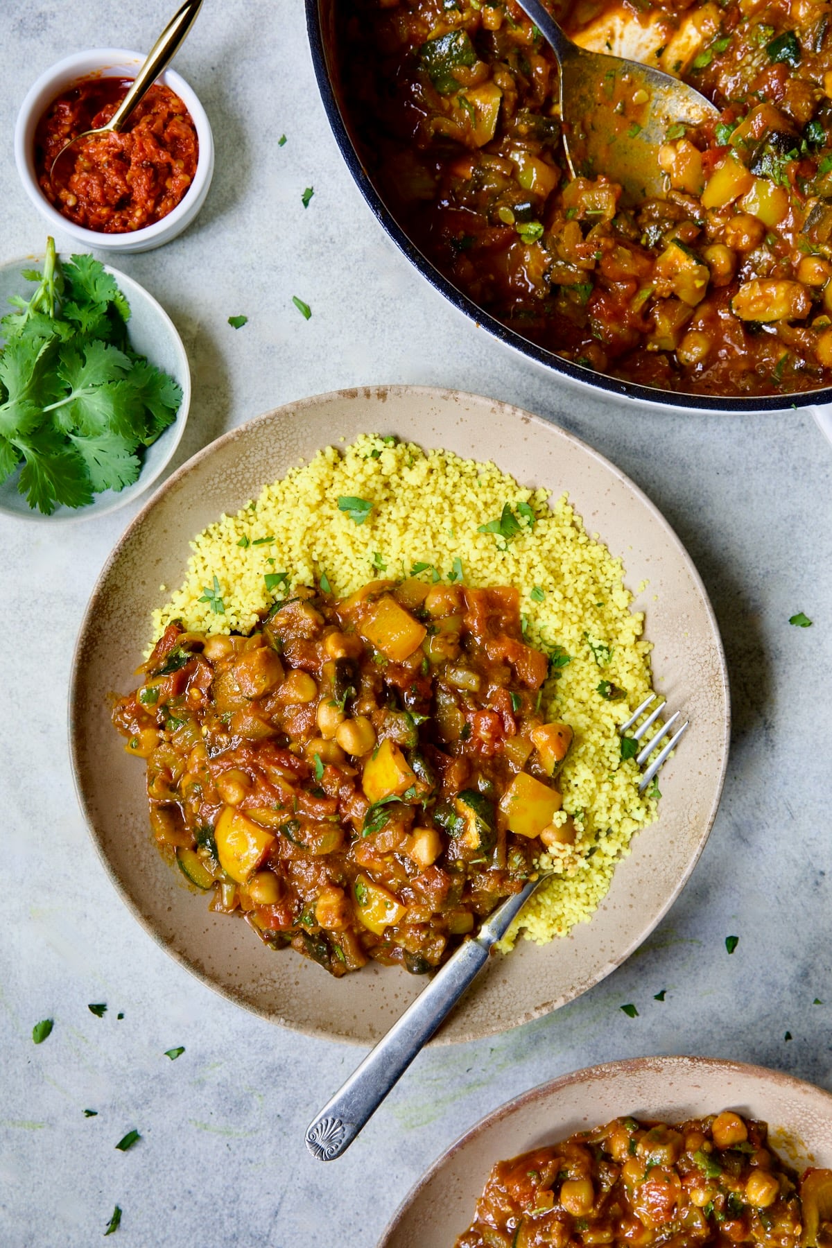 One serving of Moroccan Eggplant Stew and couscous in earthenware bowl with dinner fork.