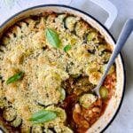 Summer Vegetable Cassoulet in white enamel cast iron skillet with serving spoon scooping some up.