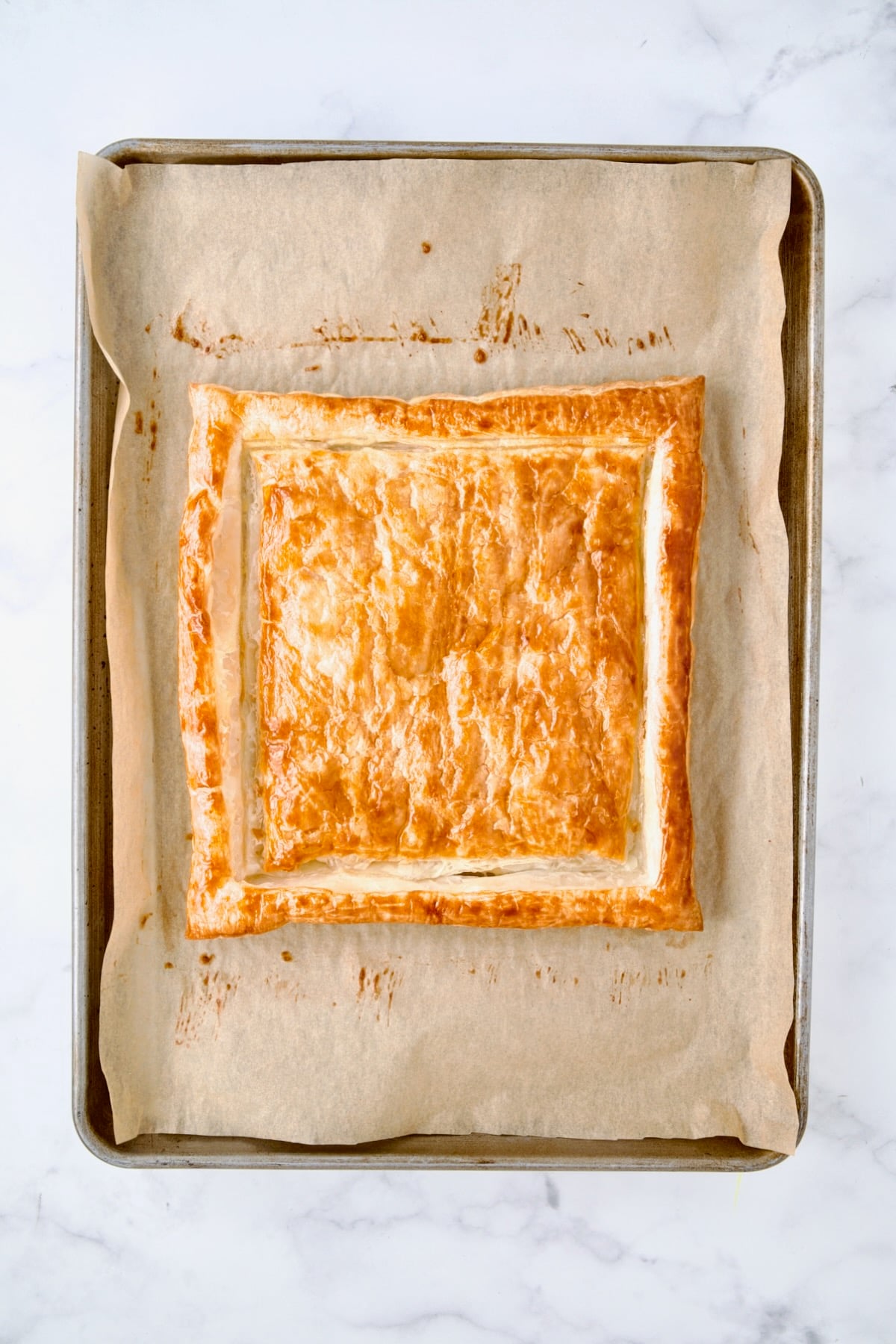 Baked puff pastry crust on parchment paper-lined baking sheet.