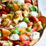Panzanella with Preserved Lemon Viniagrette on oval white platter with gold serving utensils.