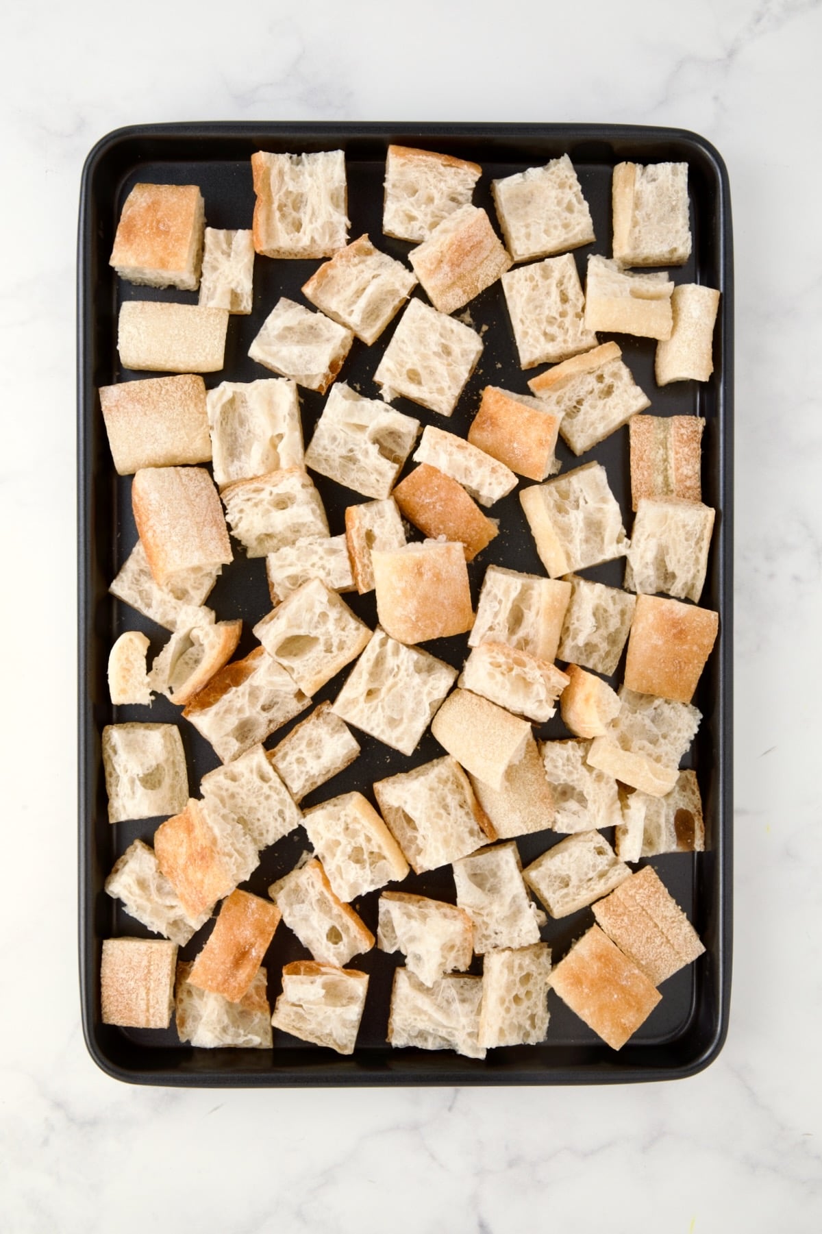 Fresh bread cubes on rimmed sheet pan.