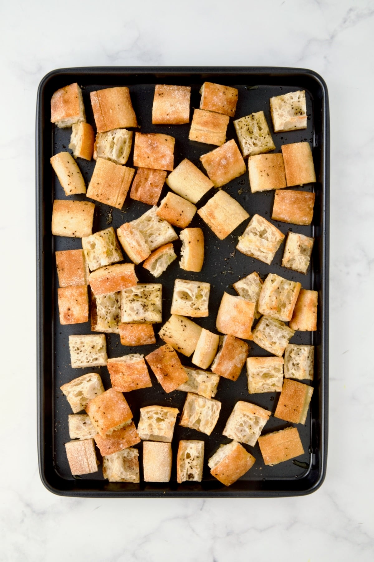 Toasted bread cubes on rimmed sheet pan.