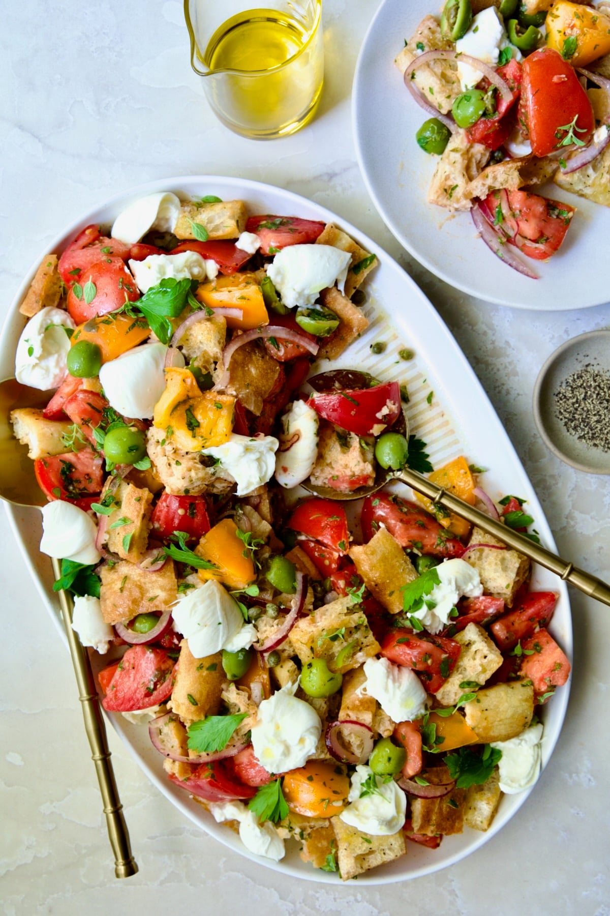 Panzanella with Preserved Lemon Viniagrette on oval white platter with some served on round white plate.