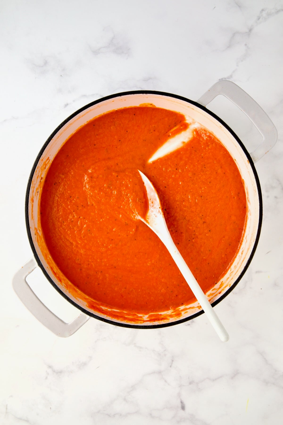 Pureed tomato sauce in white enamel cast iron skillet.