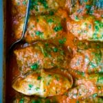 Golumpki Recipe (Polish Stuffed Cabbage) in white baking dish with serving spoon.