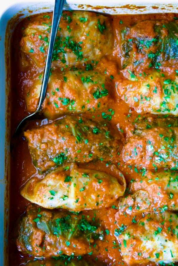 Golumpki Recipe (Polish Stuffed Cabbage) in white baking dish with serving spoon.