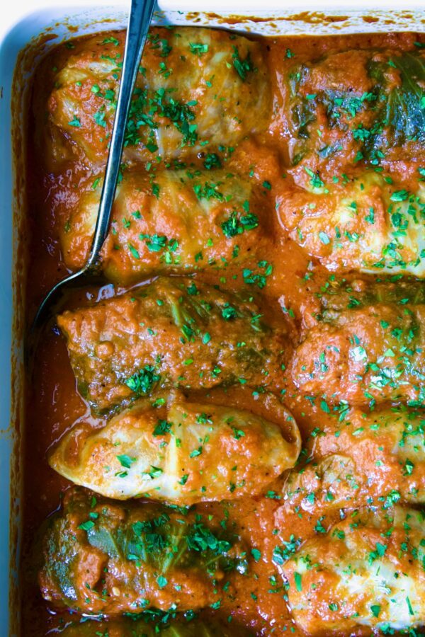Golumpki Recipe (Polish Stuffed Cabbage) in white baking dish with serving spoon.