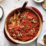 Turkish Eggplant Casserole in round red baking dish with serving utensil with a piece removed.
