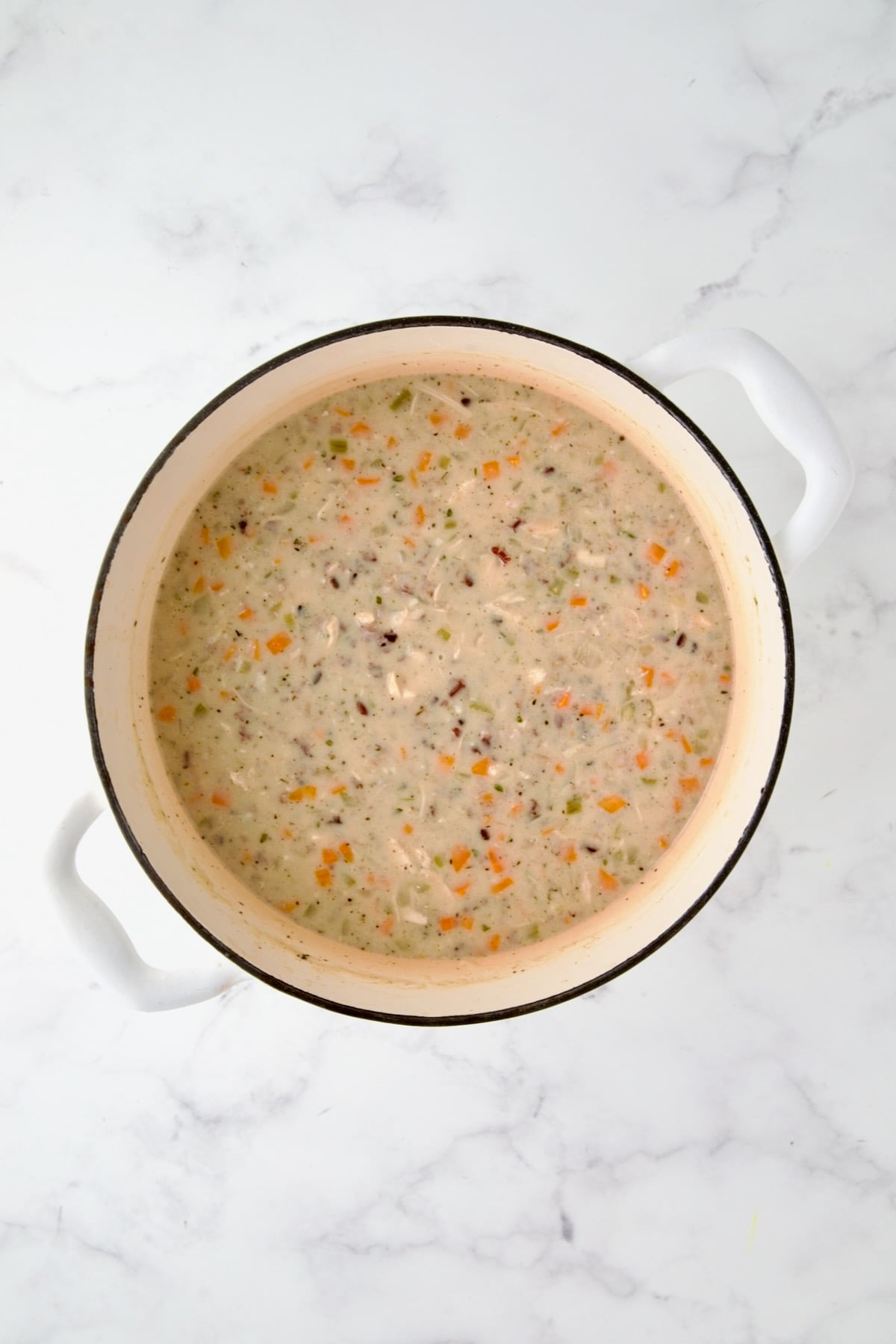 Finished Chicken and Wild Rice Soup in white enamel Dutch oven.