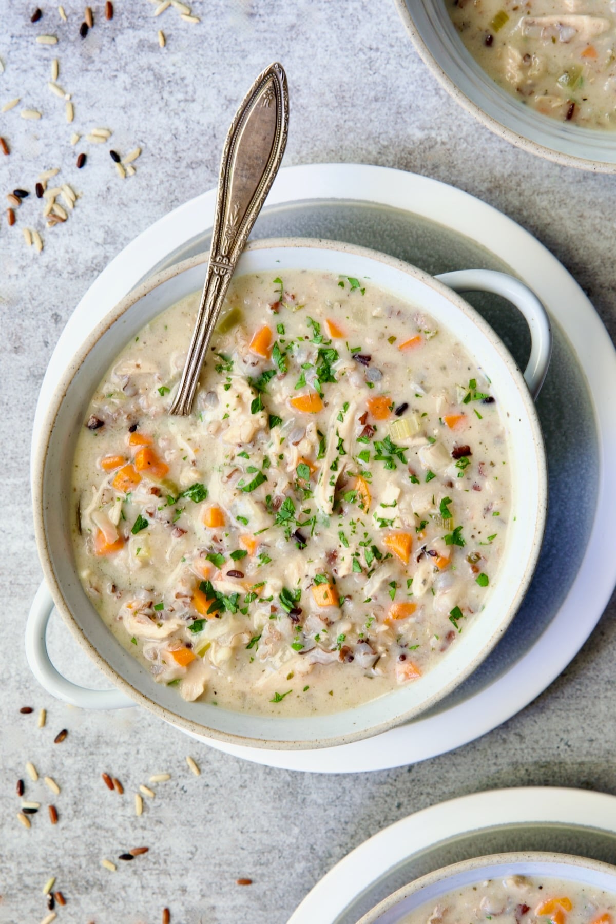 One serving of Creamy Chicken and Wild Rice Soup in white bowl with spoon.