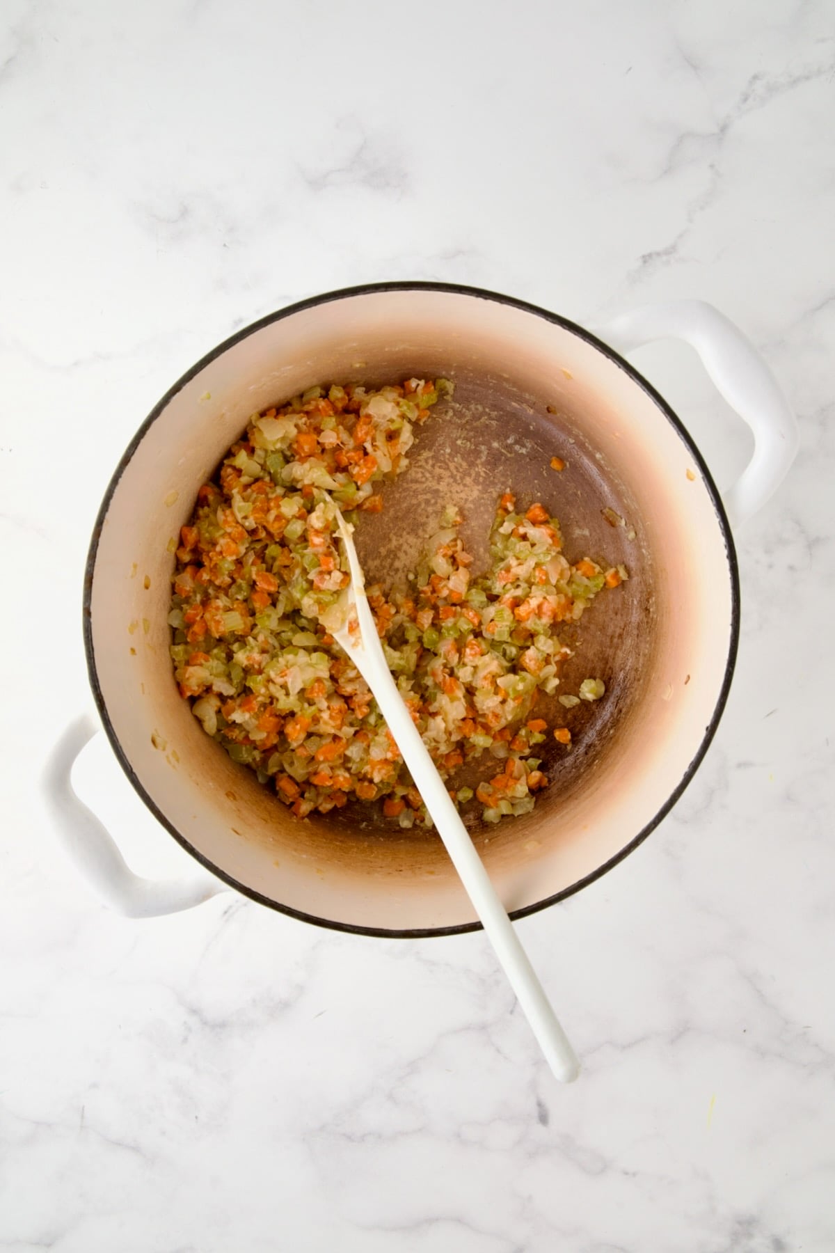 Cooked onion, carrot and celery in white enamel Dutch oven with flour stirred in.
