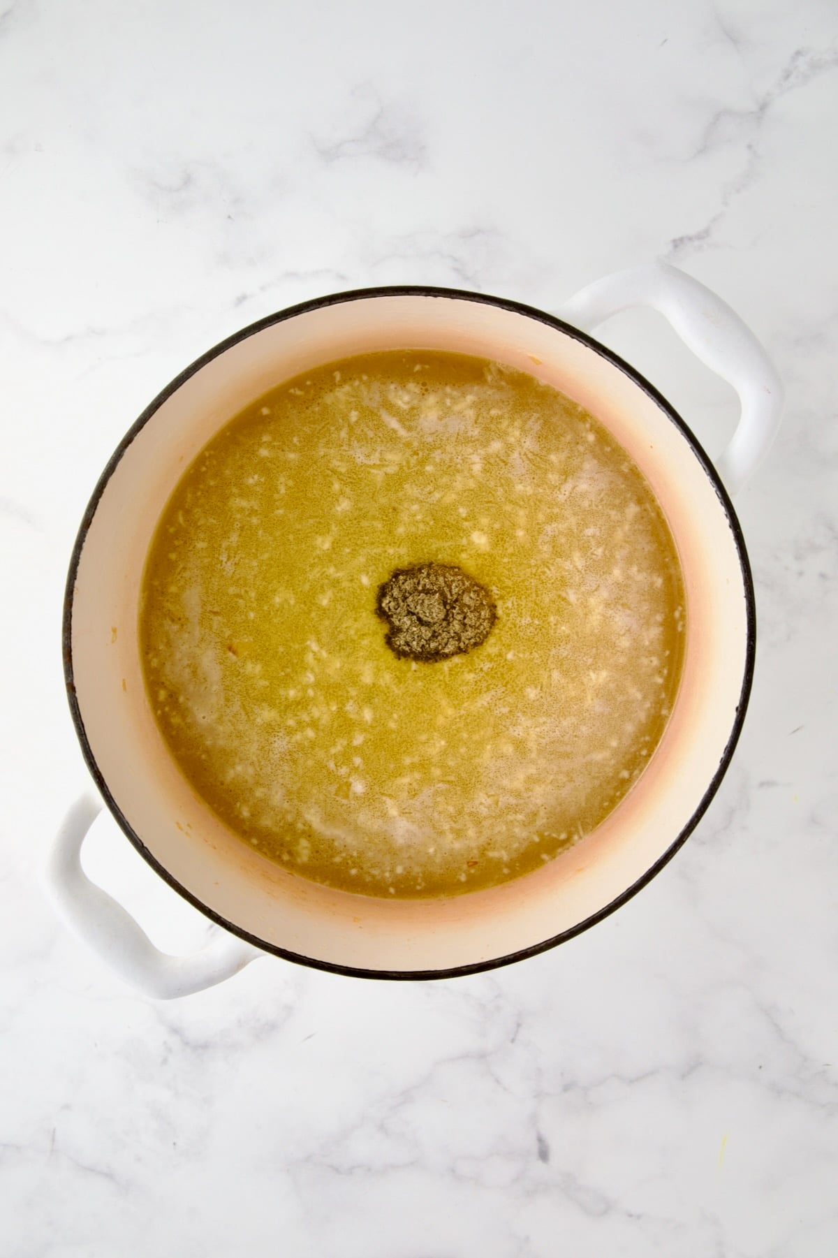 Chicken broth and poultry seasoning added to cooked onion, carrot and celery in white enamel Dutch oven.